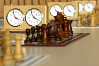Schachfiguren mit Uhr im Hintergrund